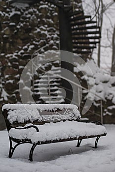 A snow-covered bench in the park. A bench covered with snow by t