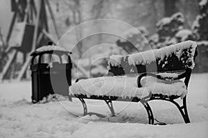 A snow-covered bench in the park. A bench covered with snow by t