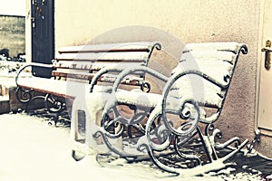 Winter time. Snow-covered bench and rocking chair in the courtyard of the house