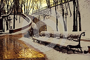 Snow-covered benches in the park, golden sunset