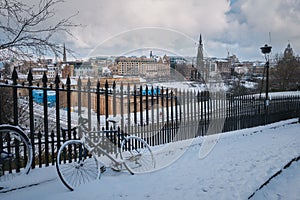 A snow-covered bike leaning against a fence