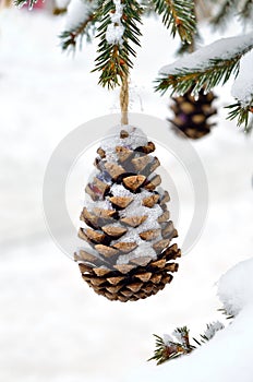 Snow covered branches of the Christmas tree decorated with toys. New Year`s decorations made of pine cones
