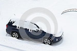 Snow covered car in the city on a winter day