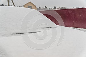 Snow covered car on metal fence background