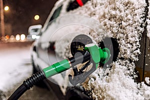 Snow covered car refueling at the gas station