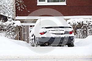 Snow-covered car in the street covered with a thick layer of snow on a winter day