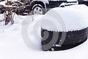 Snow-covered car tires. Summer tires in snowdrift of snow close-up.