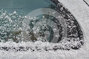 Snow-covered car window, natural background, first snow