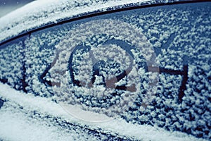Snow-covered car window with numbers 2024