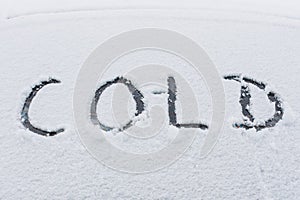 Snow covered car with word COLD on window