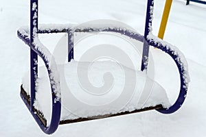 Snow-covered children`s swings. Winter landscape.