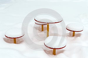 Snow-covered children`s table and benches. Snow caps on baby swing.