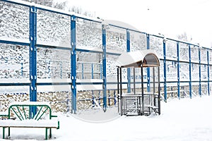 Snow-covered courtyard of a residential quarter: high fence sports basketball court, bench, gazebo. Winter snow atmosphere