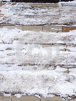 snow-covered doormats on outdoor steps of porch