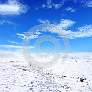 Snow covered empty frozen landscape of mountainside over blue sk