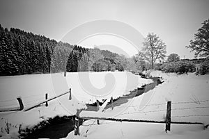 Snow covered field with creek