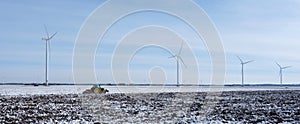 snow covered fields and tractor in dutch polder of flevoland under blue sky
