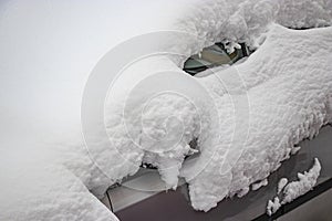 Snow-covered frozen car covered with snow. Winter road. Danger of winter driving. Car snow removal. Dangerous traffic situation