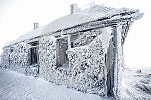 snow covered frozen hut in mountains in winter