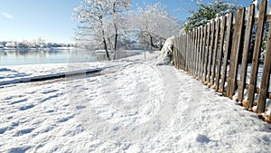 Snow-covered ground by a wooden fence with a duck swimming