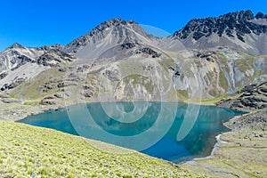 Snow covered high mountain and blue lake in Andes