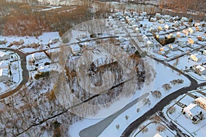 The snow covered landscape of the snowy winter landscape around the American town home complex near the small river