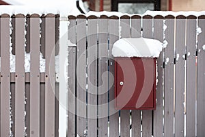 A snow-covered mailbox by a wooden fence, a snowy day