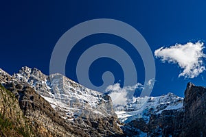 Snow-covered majestic mountain peaks with dark blue sky and flowing clouds.