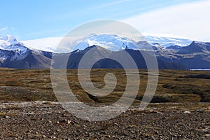 Snow-covered majestic mountains. A brown field. Icelandic landscape