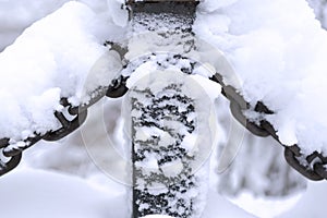 Snow-covered metal chain on the white snowy background