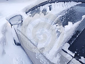 Snow-covered mirror of a car. Car in with bliss after a heavy snowfall