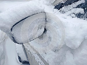 Snow-covered mirror of a car. Car in with bliss after a heavy snowfall