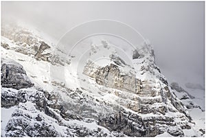 Snow covered mountain peak with little visibility due to cloud cover and snowfall.