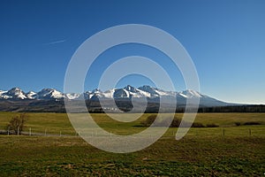 Zasnežené horské štíty s trávnatou krajinou na jar Vysoké Tatry Slovensko