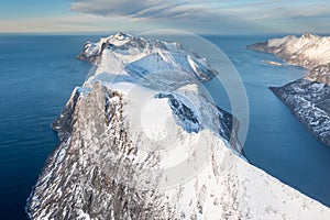 Snow covered mountain range on coastline in winter, Norway. Senja panoramic aerial view, Troms county, Fjordgard