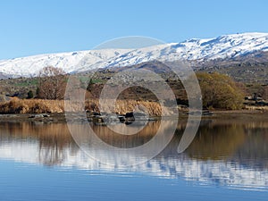 Snow covered mountain range reflected in lake at Butcher's Dam, Central Otago, New Zealand