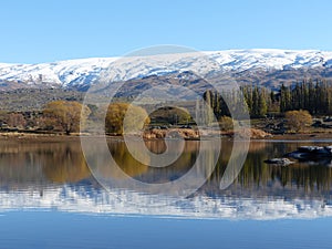 Snow covered mountain range reflected in lake at Butcher's Dam, Central Otago, New Zealand