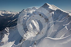 Snow-covered mountain range with traces of skis and snowboards