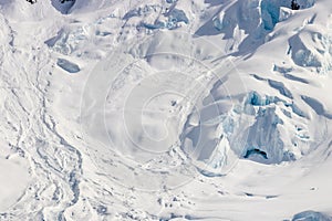 Snow covered mountain slope, Antarctica. Rocks, blue ice. Cloudy sky.