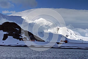 Sun dappled mountain in Antarctica with a science station below photo