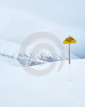 Snow Covered Mountains with Avalanche Danger Sign