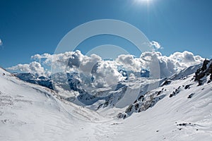 the snow-covered mountains clouds rise dramatically from the valley