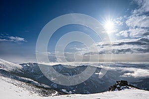 Snow covered mountains with clouds and sun with fog in valley, Slovakia Low Tatras Dumbier