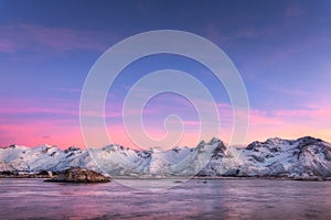 Snow covered mountains and colorful sky reflected in water