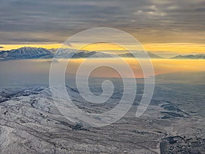 Snow covered mountains overlooking Salt Lake City in winter with glow of rising sun