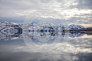 Snow-covered mountains reflect symetrically in Okanagan Lake, West Kelowna