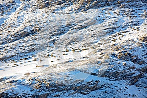 Snow-covered mountainside at sunset. You can see an abandoned building and two grazing deer