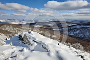 snow-covered mountaintop, with view of rolling hills and valleys below