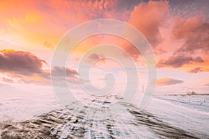 Snow-covered Open Slippy Road During A Snowstorm Blizzard In Winter. Altered Colorful Sunset Sunrise Sky. Dangerous