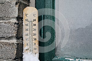 Snow covered outdoor thermometer on windowsill. Winter, weather forecast and temperature measure concept. Freeing season